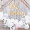 Gold wooden sign spelling out Oh Baby decorated with white balloons and greenery