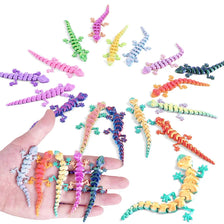 A hand holds a collection of colorful, articulated 3D-printed gecko fidget toys.