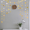 A decorative garland featuring gold and silver stars and polka dots hangs on a gray wall above a wooden clock.