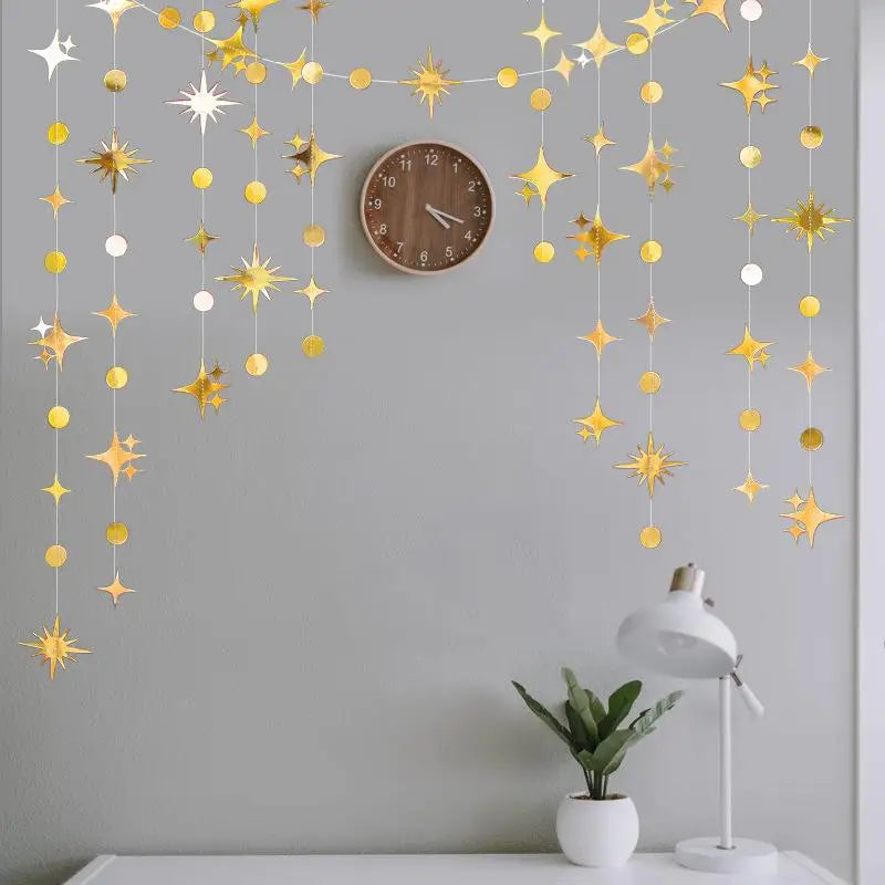 A decorative garland featuring gold and silver stars and polka dots hangs on a gray wall above a wooden clock.