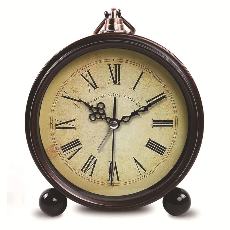 A vintage metal battery alarm clock with a round face and Roman numerals, set against a light brown background.