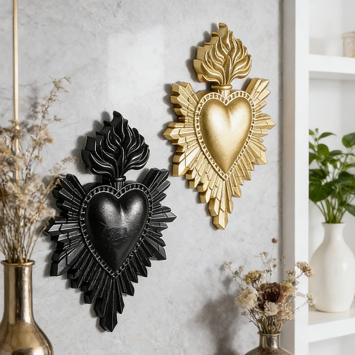 Two gold and black flame heart resin wall decorations mounted on a gray wall.