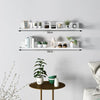 A white floating wall shelf with multiple compartments displaying small potted plants and decorative items.