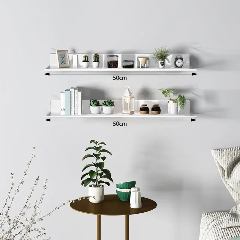 A white floating wall shelf with multiple compartments displaying various small potted plants and decorative items.