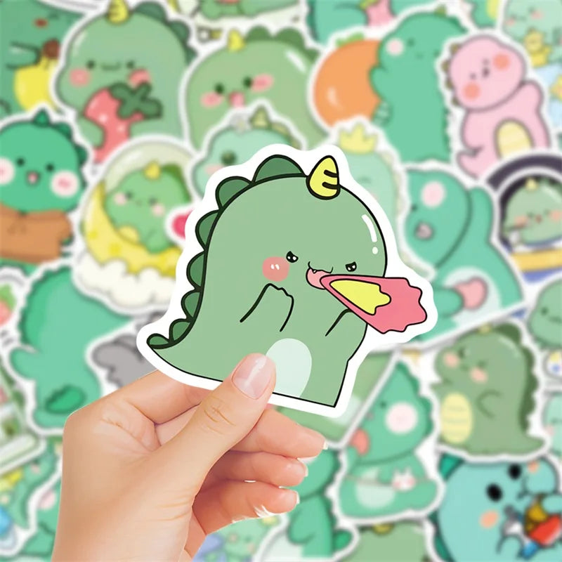 A hand holds a cute green dinosaur PVC sticker against a background of various pastel-colored dinosaur stickers.