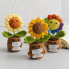 Three handmade crochet sunflower desk companions with smiling faces and green leaves.