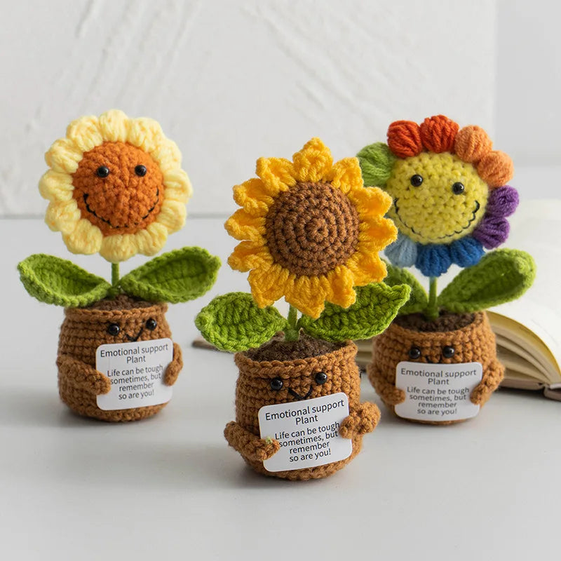 Three handmade crochet sunflower desk companions with smiling faces and green leaves.