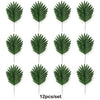 Twelve artificial tropical palm leaves in various shades of green arranged for party decor