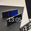 A black LED digital alarm clock displaying 1:08 is shown on a dark surface.