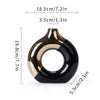 A black and gold ceramic ring-shaped vase with a curved neck.