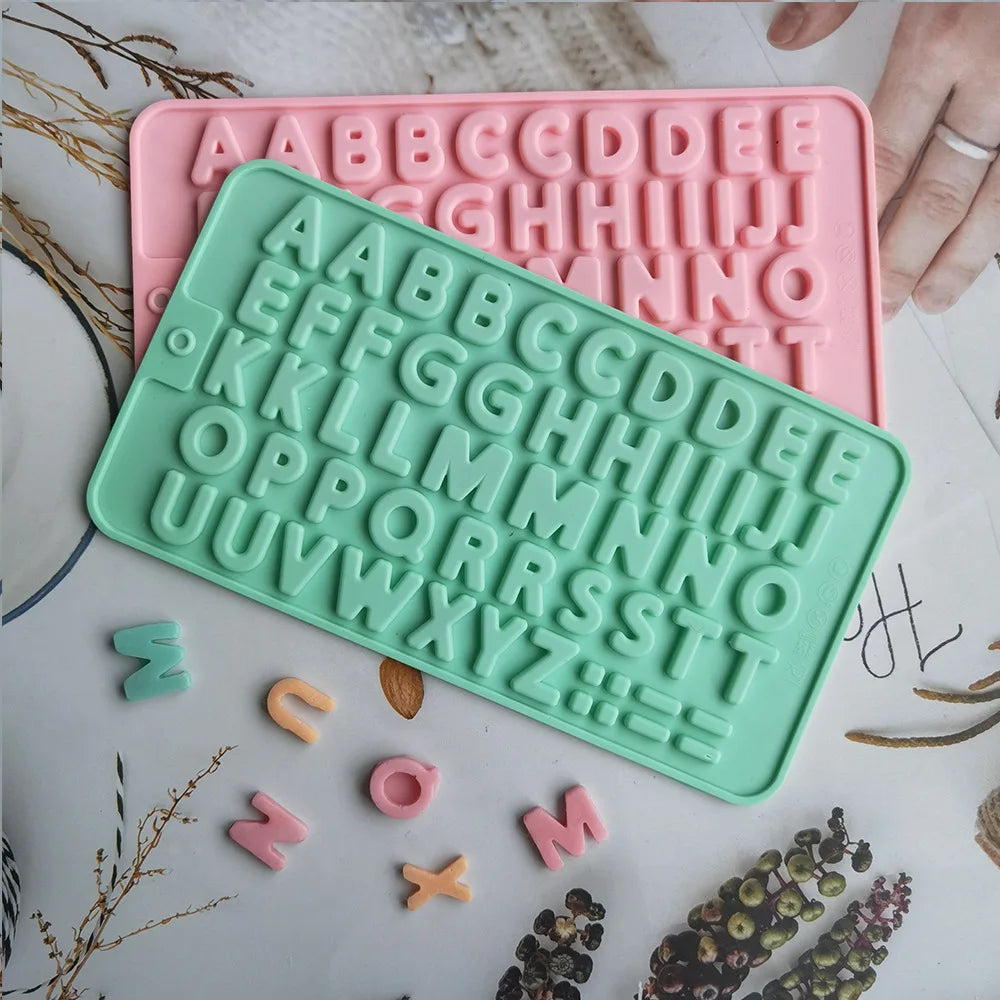 A silicone mold set with pink and mint green alphabet letters and numbers for baking