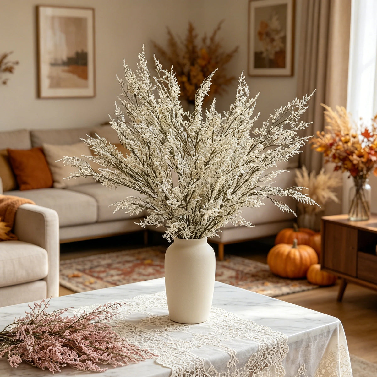 A vase filled with white artificial silk lover grass on a light-colored table in a living room setting.