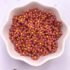 A small white dish filled with reddish-pink resin flower gems with yellow centers.