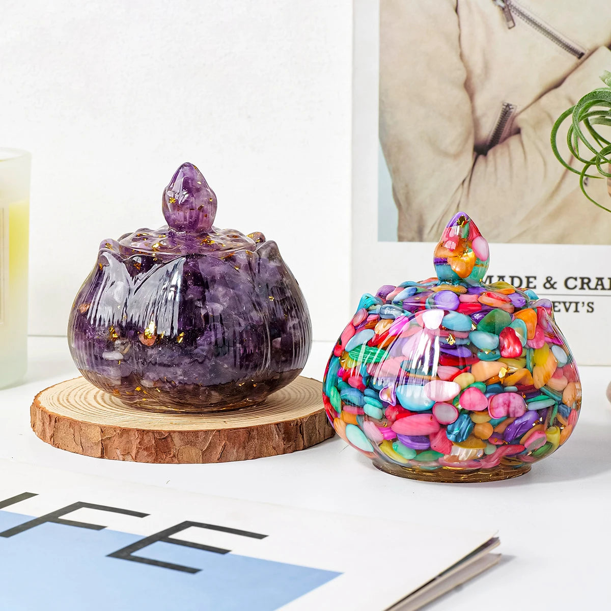 A dark purple crystal bowl with a pointed top sits next to a colorful glass bowl filled with small, sparkling stones.