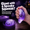 A hand holds a glowing purple silicone fidget dumpling product with a spooky face design.