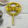 A gold acrylic birthday cake topper featuring the words Happy Birthday on a circular plaque mounted on a stick.