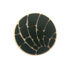 A circular black silicone shoe charm with a textured, segmented pattern.