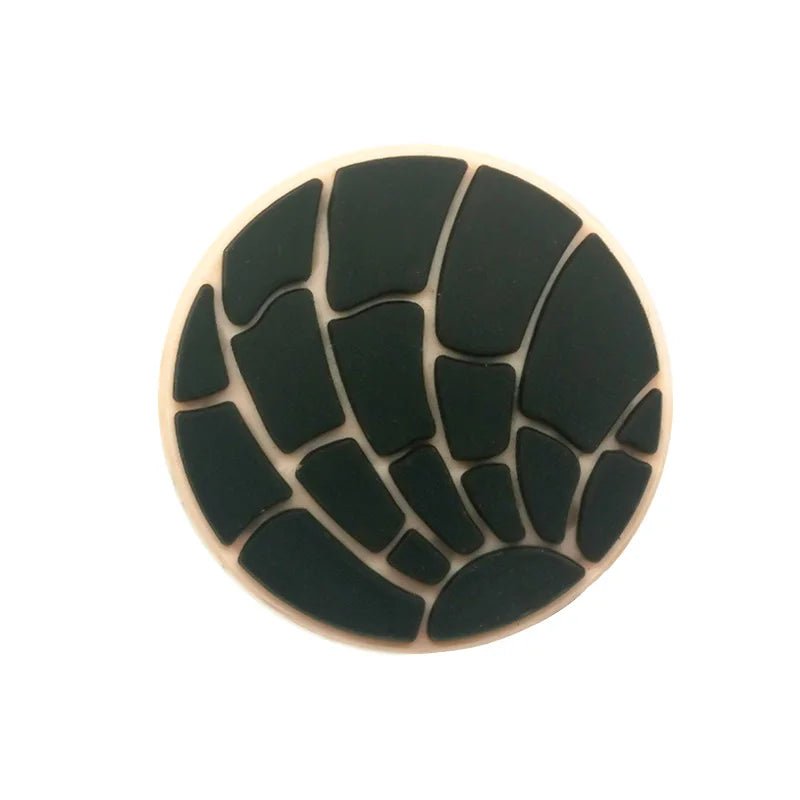 A circular black silicone shoe charm with a textured, segmented pattern.