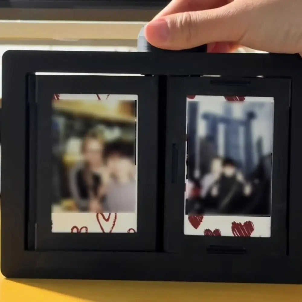 A hand is holding a black 3D rotating photo holder with two clear display pockets.
