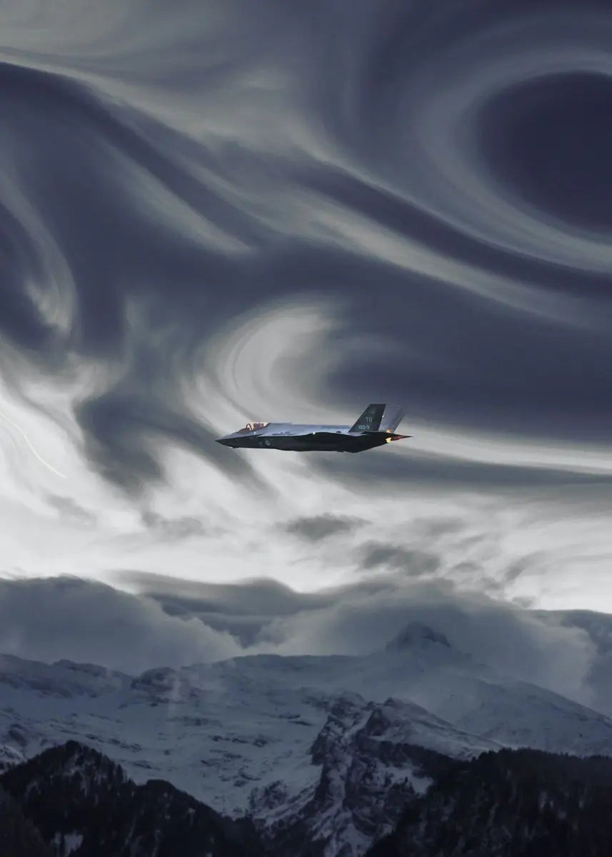 A military jet aircraft flying through swirling clouds above a snowy mountain landscape.