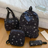 A set of black bow print backpack and matching accessories resting on a light-colored surface.