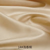 Close-up of smooth beige satin fabric draped and folded to show its sheen and texture.