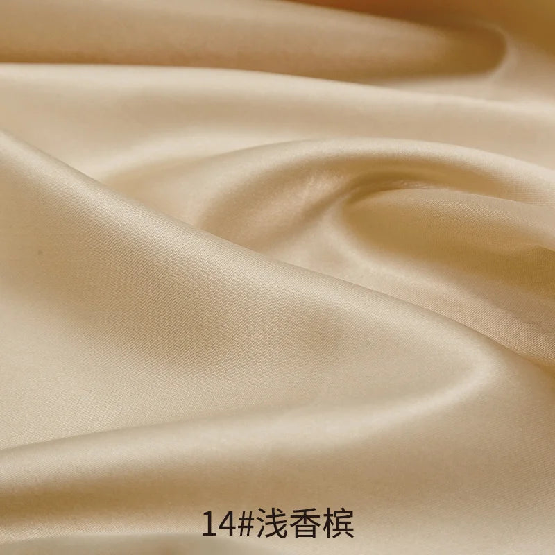 Close-up of smooth beige satin fabric draped and folded to show its sheen and texture.