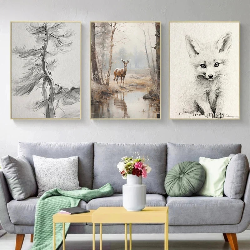 A gallery wall featuring three framed canvas prints of forest animals, including a deer and a fox, displayed above a gray sof