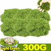 A hand is holding a large clump of light green artificial moss for home décor and DIY projects.