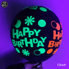 A black latex balloon with neon green and orange lettering spelling out Happy Birthday