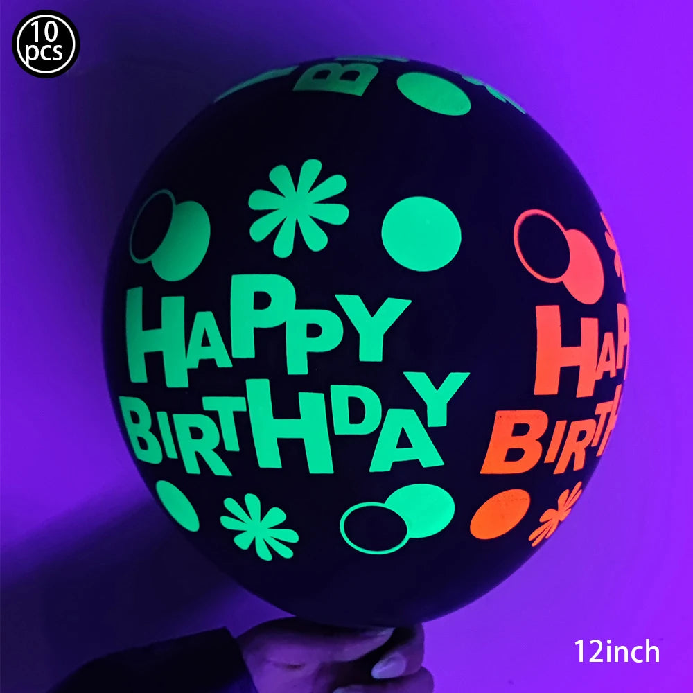 A black latex balloon with neon green and orange lettering spelling out Happy Birthday