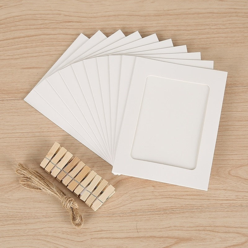A set of white kraft paper photo frames and wooden clips displayed on a light wood surface.