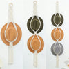Handmade macrame hat organizer with a wooden dowel hanging on a white wall.