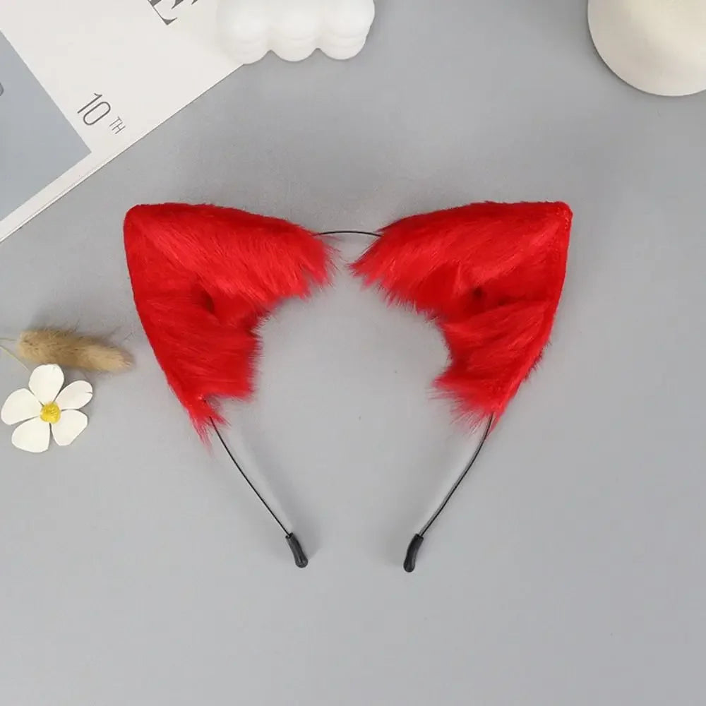 A pair of bright red plush fox ears headband with black strings and a small white flower nearby.