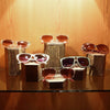 A display rack featuring several pairs of sunglasses and eyeglasses resting on wooden hexagonal stands.