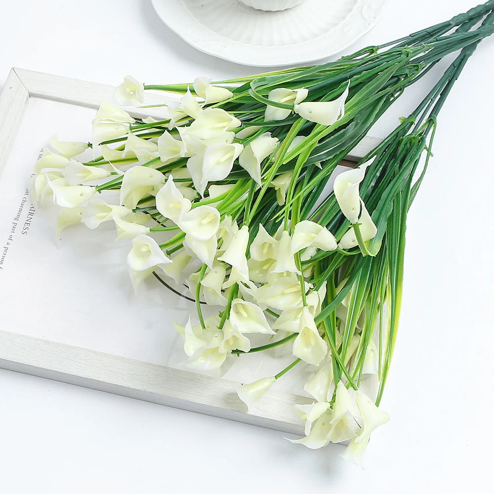A bouquet of white artificial calla lily flowers on a wooden tray.