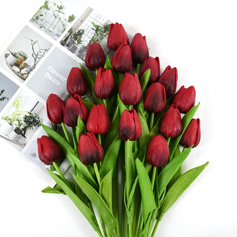 A bouquet of deep red artificial tulips with green stems and leaves.