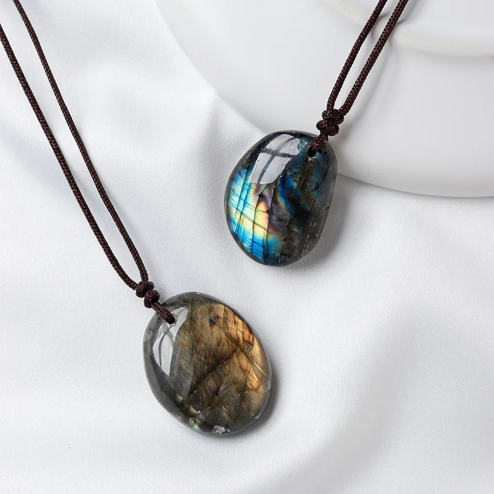 A dark, polished labradorite gemstone pendant on a brown leather cord, displayed on a white background.