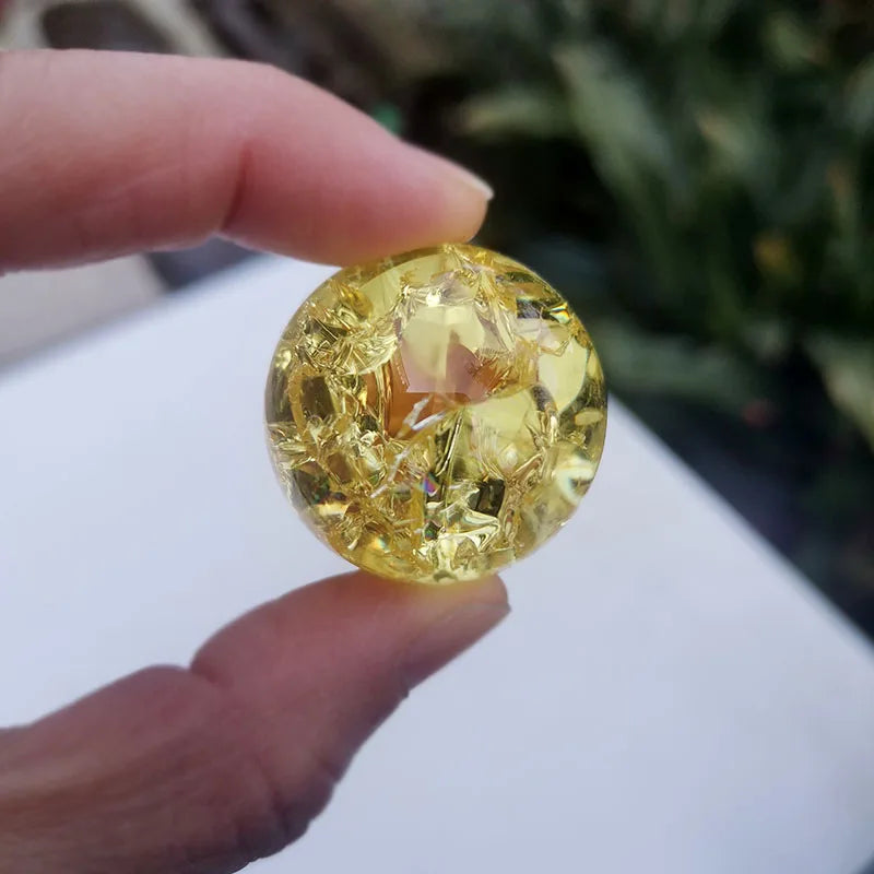 A hand holds a faceted, golden-yellow crystal ice crack ball used as water fountain decor.