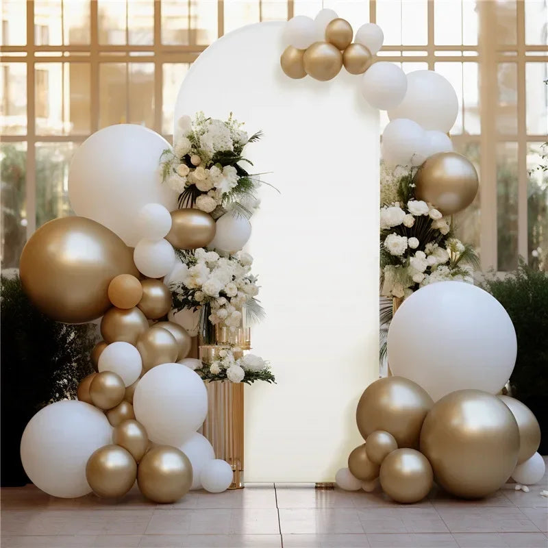 A white arch backdrop decorated with gold and white balloons in a bright indoor setting.