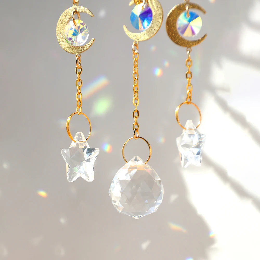 Three gold moon-shaped crystal pendants with rainbow prism accents hanging against a light background.