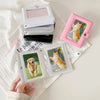 A pink compact photo card holder album with a clear cover displaying a cat and a dog photo, resting on a white cloth.