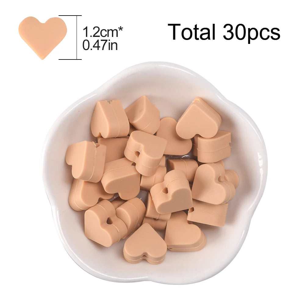 A bowl filled with 30 small, light peach-colored silicone heart beads for DIY jewelry making.