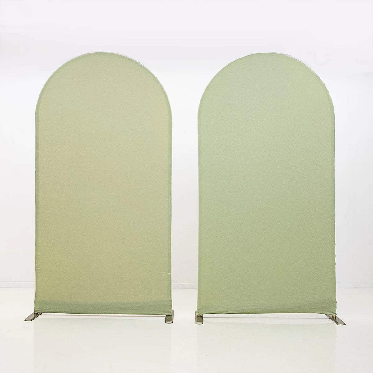 A pair of light sage green stretchable arch backdrop covers displayed against a white background.