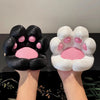 A pair of hands holds a black and pink cat paw silicone phone stand with a stress relief design.