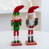 A handcrafted wooden nutcracker soldier figurine dressed in a red Santa hat and green outfit.