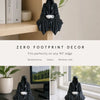 Black resin ghost statue with a tea cup sits on a wooden shelf.