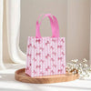 Pink and white striped gift bags with pink bows and heart cutouts displayed on a wooden tray