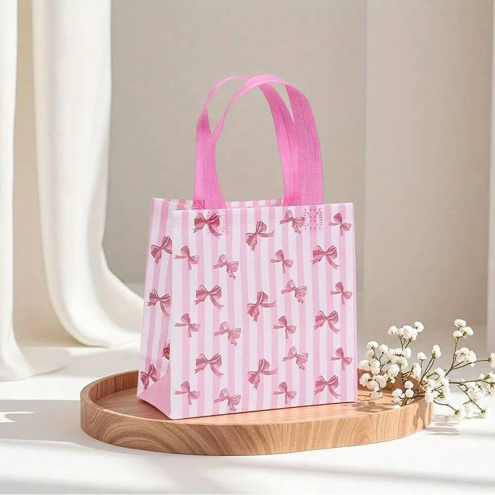 Pink and white striped gift bags with pink bows and heart cutouts displayed on a wooden tray