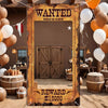 A rustic western photo booth backdrop featuring a wooden frame, horse design, and a reward sign for $10000